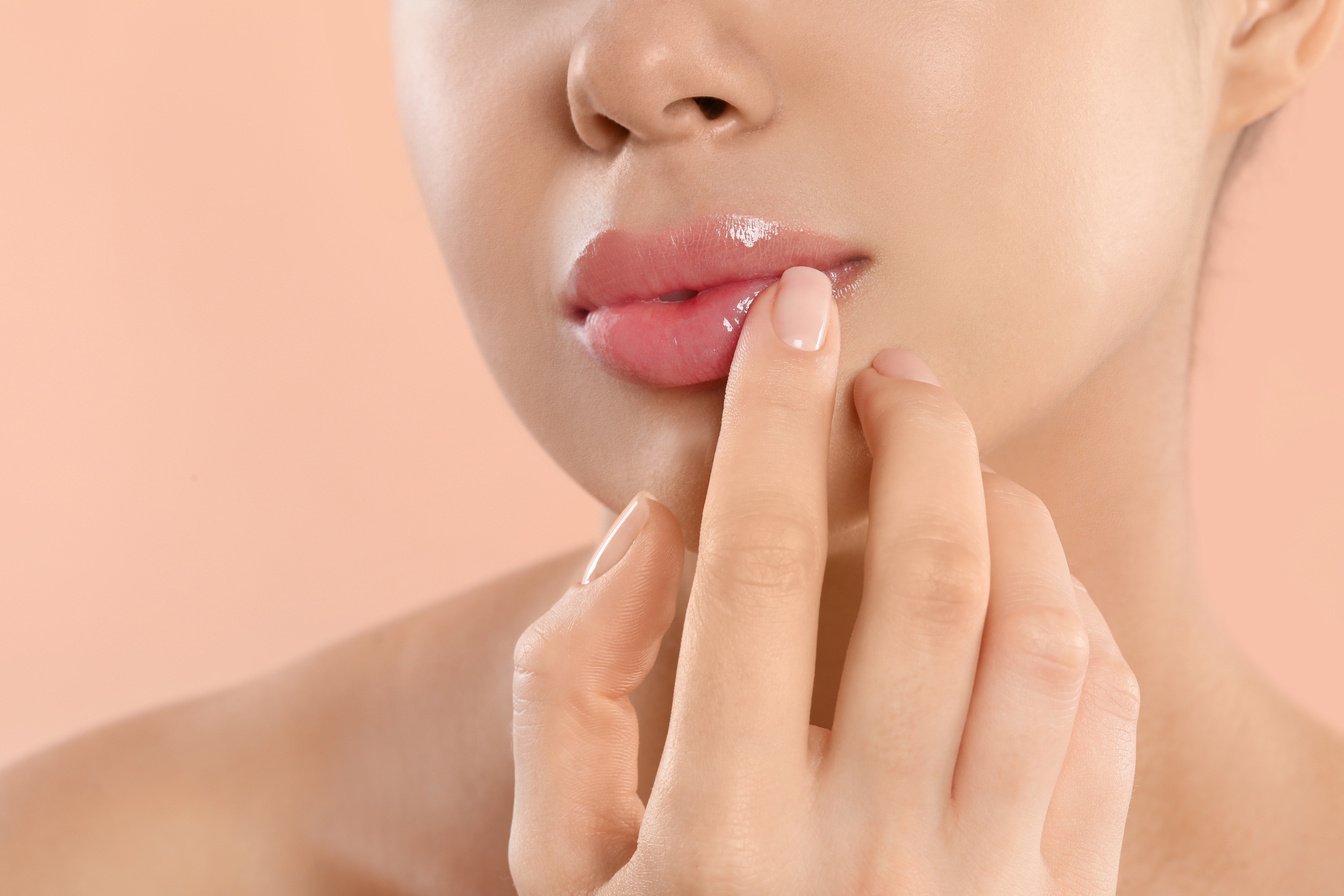 Young Woman with Beautiful Full Lips on Peach Background, Closeup